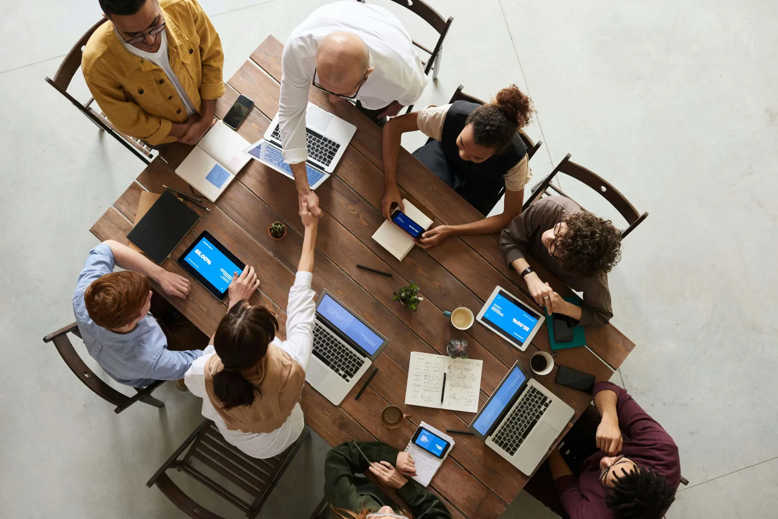 Equipo de trabajo reunido alrededor de una mesa con laptops